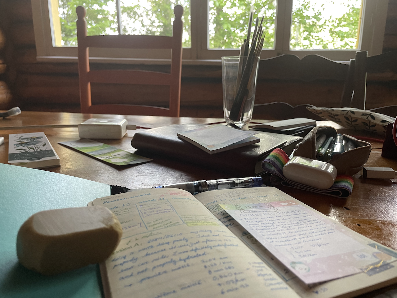 Sur une table, des cahiers et du matériel d'art.