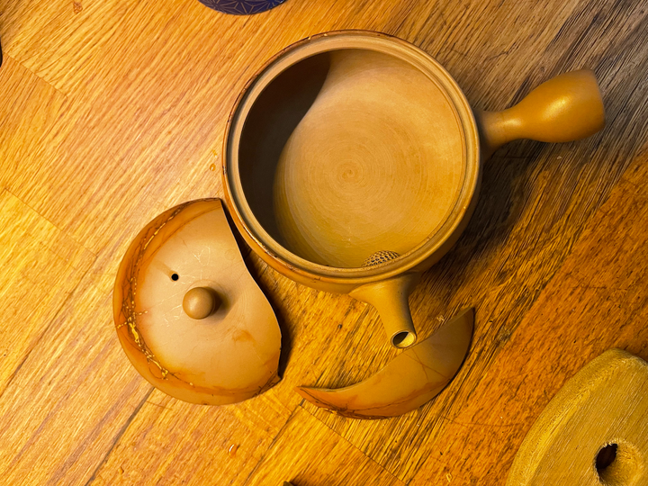 Une théière en céramique avec un couvercle brisé en deux.